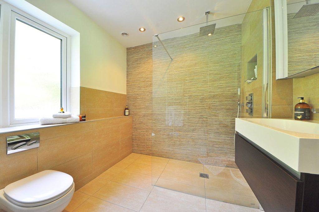 Bathroom with large windows and glass shower divider with ceramic countertop and tile floor