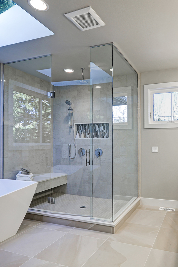cropped shower with glass shower door and shower seat with tile flooring and freestanding tub